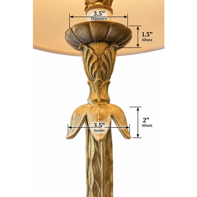 Elegant vintage table lamp featuring an ornate gold-tone sculptural metal body with intricate leaf and floral detailing....