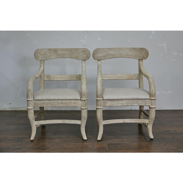 A pair of Swedish whitewash painted wood armchairs from the Midcentury period, with open backs, custom upholstered seats,...