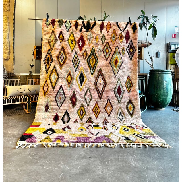 This contemporary Moroccan Boujad rug features a vibrant diamond pattern handwoven on a soft pastel background. Inspired...