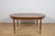 This is an oval-shaped teak dining table manufactured by G-Plan in the 1960s. The table has reinforced edges of the top....