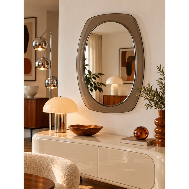 Vintage oval mirror with soft, organic lines, highlighted by a wide smoked glass frame. Its refined aesthetic evokes 1970s...