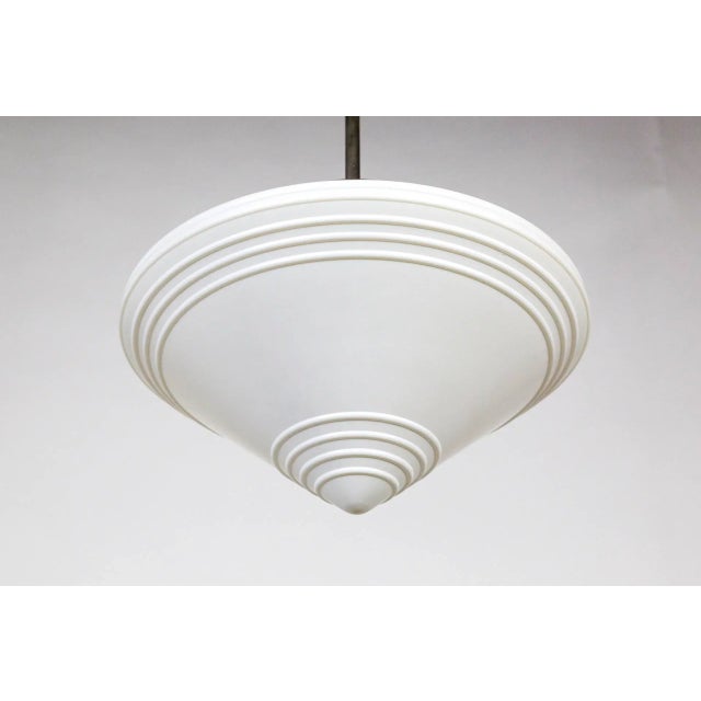 A large, beautifully shaped, streamlined, spinning top pendant; in milk glass with molded ribbed details on the point and...