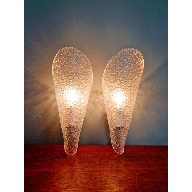 Pair of cone-shaped wall sconces in textured, clear plastic, circa 1970. Each sconce is compatible with an E14 LED bulb....