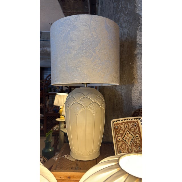 A stately white ceramic table lamp base with Art Deco fan and ginkgo leaf relief in arched panels, topped with a large...
