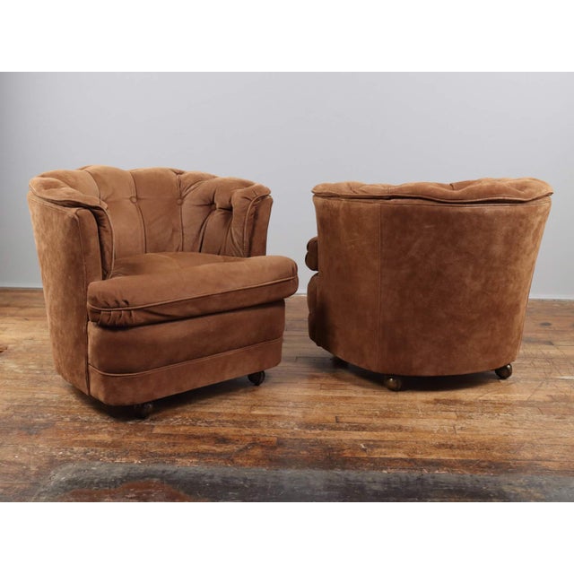 A pair of leather barrel chairs on casters, upholstered in thick, full-grain leather. The chairs are comfortable, with...