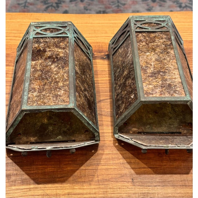An exceptional pair of vintage Arts & Crafts wall lantern sconces featuring hand-formed copper construction with a...