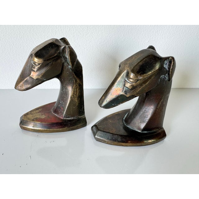 A striking pair of vintage Art Deco style brass bookends, each featuring a stylized dog head sculpted with clean, angular...