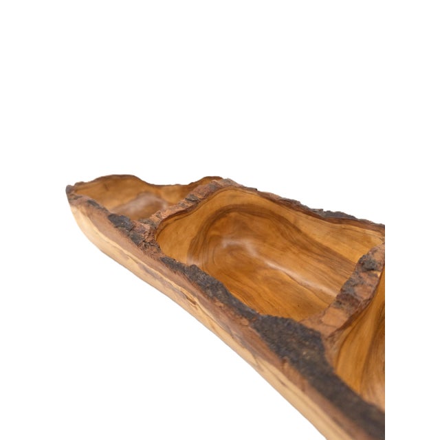A beautifully hand-carved olive wood serving tray featuring three integrated compartments, crafted by artisans in Peru....