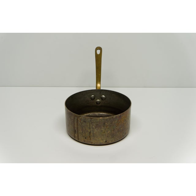 A tin lined copper sauce pot with a riveted cast brass handle. Provenance stamped next to the handle that reads "Made in...