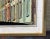 Framed oil or acrylic on canvas board of a silohuetted lady on a street of row houses. By listed Venezuelan artist Edel...