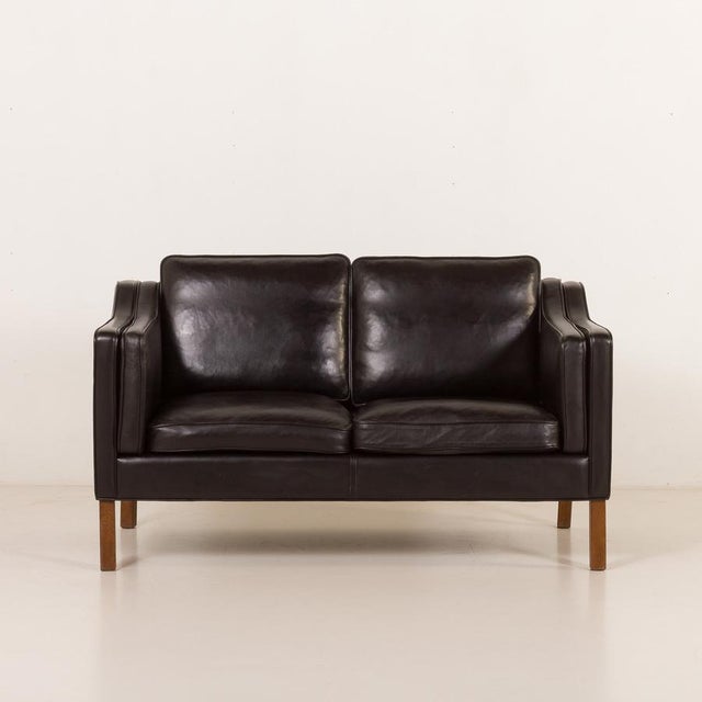 This high end elegant black leather sofa was produced by hurup in denmark in the 1980s. It is a refined example of late...