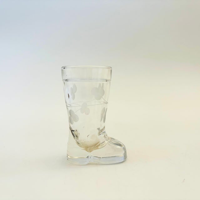 A vintage glass shot glass in the shape of a small boot. Decorated with a lovely etched floral design. Measures 2"W x 1"D...