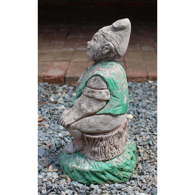 Mid-20th century cast stone seated garden gnome, English. Smiling with his pipe in hand - traces of original paint in the...