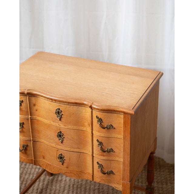 A 1970s Danish Modern oak side chest attributed to Henning Kjærnulf, showcasing sculptural lines and warm, honey-toned...