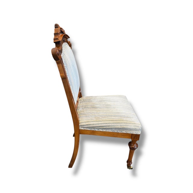 This vintage upholstered side chair features beautifully carved wood detailing, an ornate crest rail, and turned front...