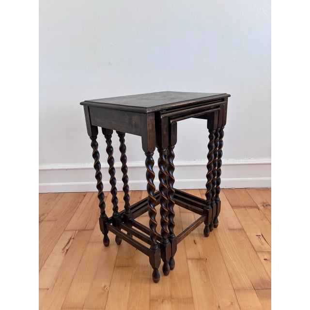 Set of three nesting tables from England 1940s These tables feature turned barley twist legs, a dark wood stained finish,...