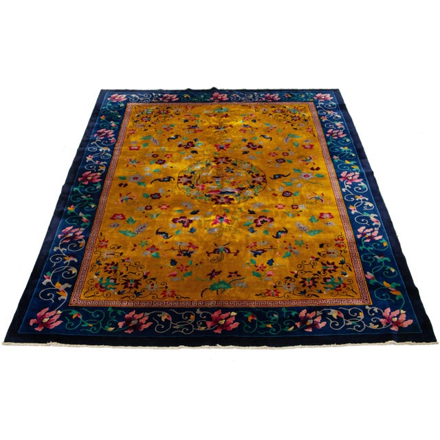 This luxurious antique Peking Chinese hand-knotted wool rug showcases a goldenrod color field embellished with a navy blue...