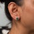 Two emerald-cut zambian emerald stones totalling 2.1 carats glow at the centre of this pair of solid 14K yellow gold...
