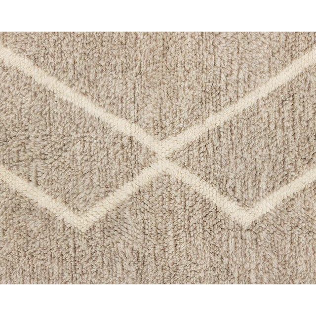 Sophisticated hand-knotted rug featuring a minimalist Sandstone hue with contrasting Ivory linear accents, a timeless...