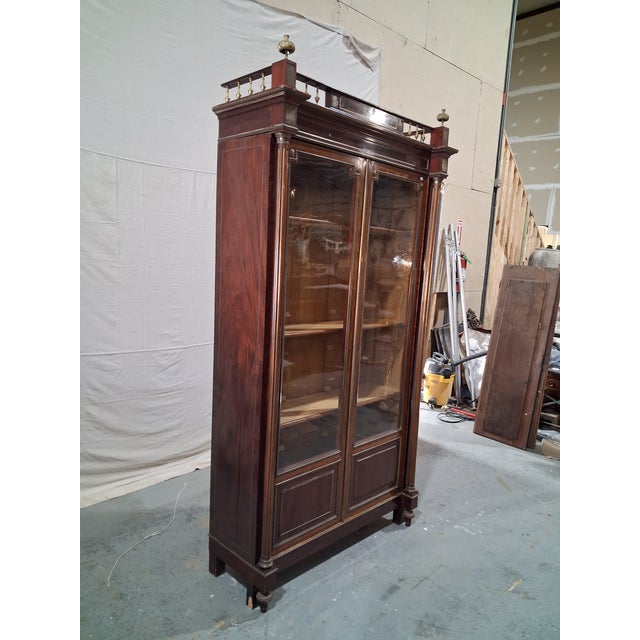 Impressive French Napoleon III library bookcase crafted in richly figured mahogany with original glass doors, brass-...