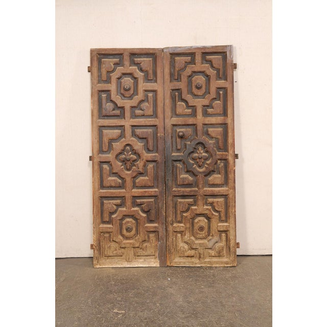 A Spanish pair of geometric panel motif carved wood doors from the 18th century. These antique doors from Spain have been...