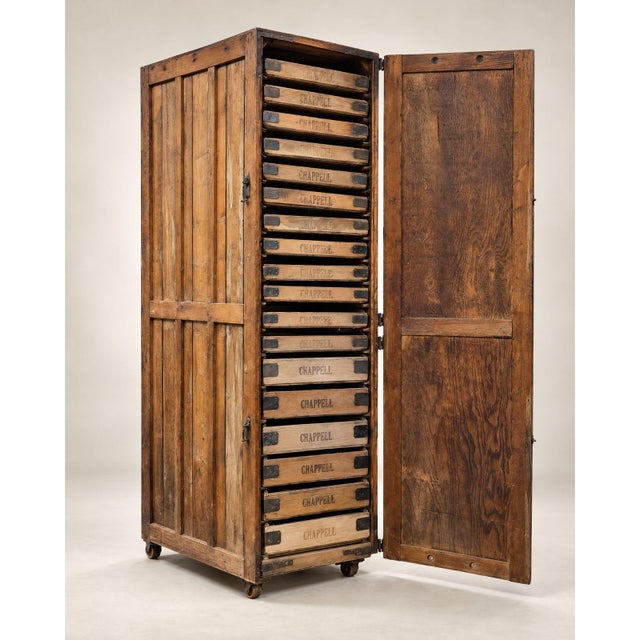 An impressive antique industrial storage cabinet featuring a towering wooden frame, a full-length hinged door, and an...