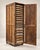 An impressive antique industrial storage cabinet featuring a towering wooden frame, a full-length hinged door, and an...
