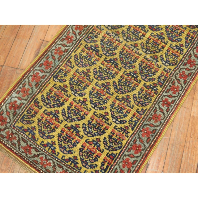 Very narrow finely woven one of a kind Persian runner with a navy paisley motif on a yellow field. Measures: 1'11" x 7'6".