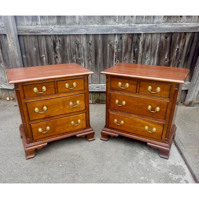 Stickley three-drawer night stands in solid wild black cherry with brass drop bail pulls. . Drawers are center-guided and...