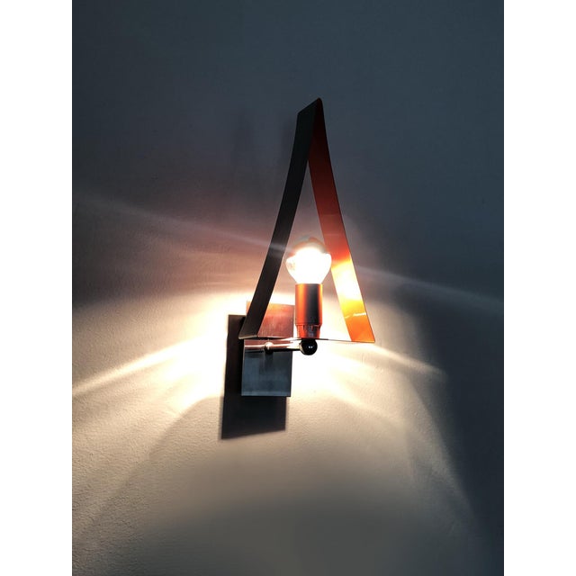 Pair of triangular wall sconces in chrome and orange metal. 1970s Pair of triangular wall sconces in chrome-plated metal...