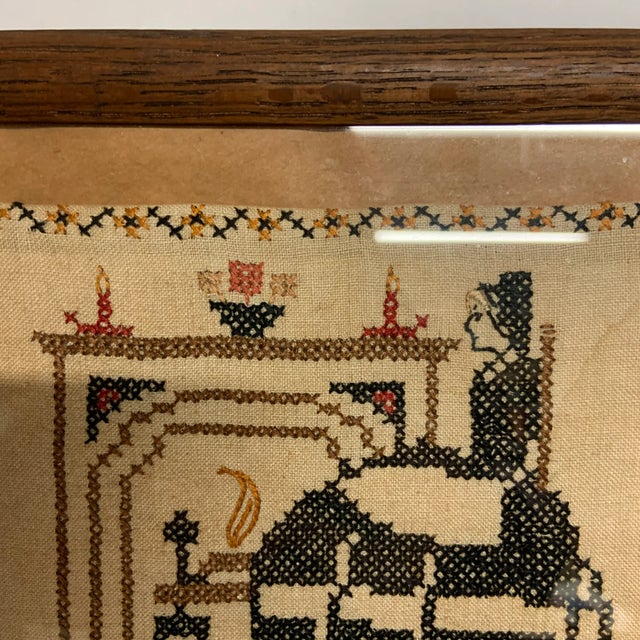 Antique cross-stitch sampler in frame ready to hang. Charming image of woman sitting by fireplace. The comforts of home...