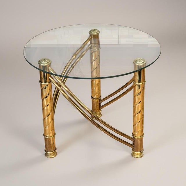 A striking pair of vintage brass-finished metal and glass side tables featuring sculptural curved stretchers and spiral-...