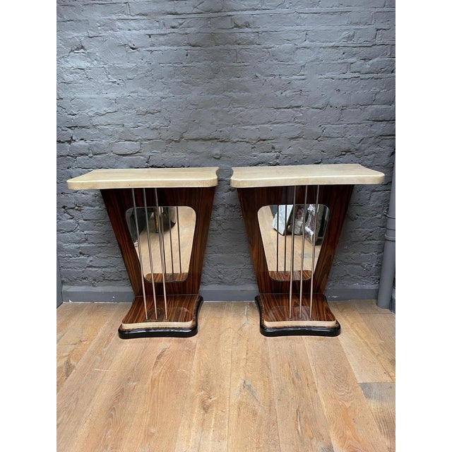 A pair of console tables with cream lacquered goatskin tops and edges, Palasander uprights and feet supported on an...