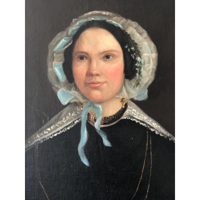 This antique oil portrait painting from the 19th century shows a Dutch lady formally dressed. She wears a black gown with...
