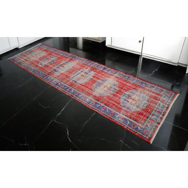 Vintage 1970s distressed Turkish Oushak rug runner. With red field and shades of green, dark gray and blue throughout....