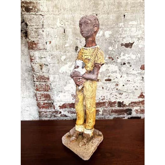Figure of a Boy holding a dog. Figure looks like it was outside for a long time and elements wore away some of the paint...
