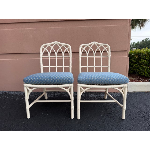 A pair of vintage McGuire dining chairs in the classic arched lattice design. Finished in white painted rattan with...
