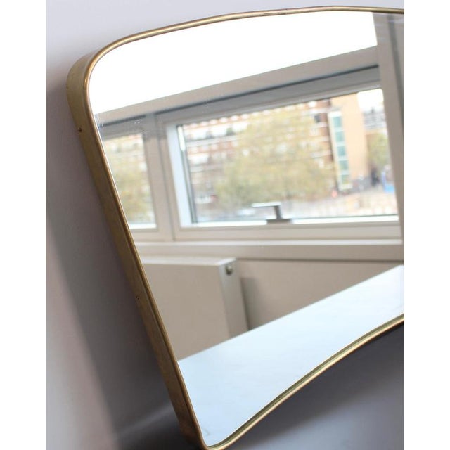 Mid-century large Italian wall mirror with brass frame (circa 1950s). The mirror is distinctively-shaped in a Modern...