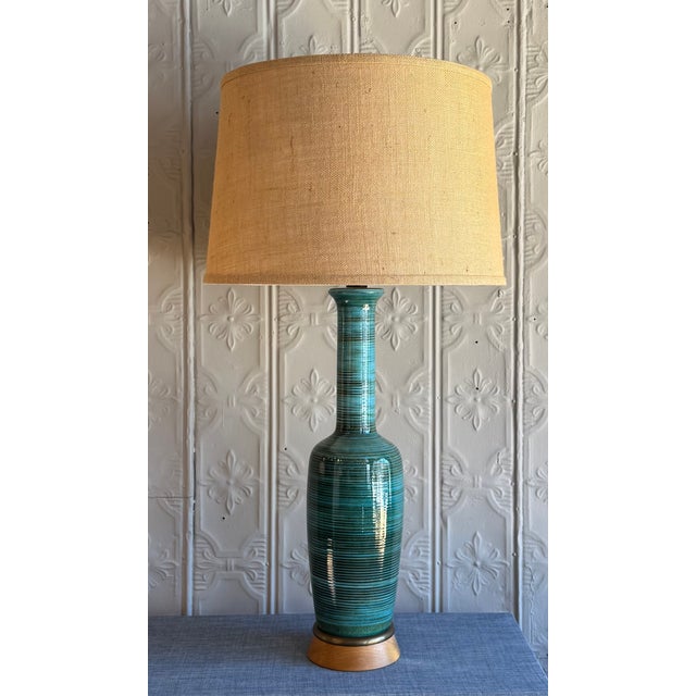 Mid-Century Ceramic Table Lamp with Wooden Base and Brass Accents. The ceramic glaze has a crackled blue finish striped...