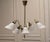 The chandelier features a refined sculptural brass construction with five gracefully angled arms, each supporting a...
