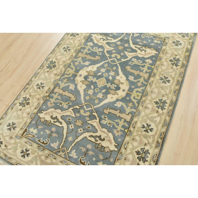 A modern tribal Oushak rug hand-knotted with an all-wool pile on a cotton foundation. This oriental rug features a central...