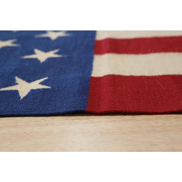 This handmade wool rug features a Kilim style flat weave construction defined by a primary color palette of coral, salmon,...