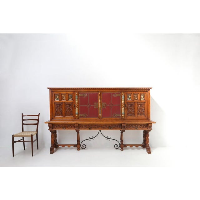 A large and richly decorated mid-century Spanish sideboard in oak with red leather and copper details and metal stretcher....