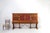 A large and richly decorated mid-century Spanish sideboard in oak with red leather and copper details and metal stretcher....