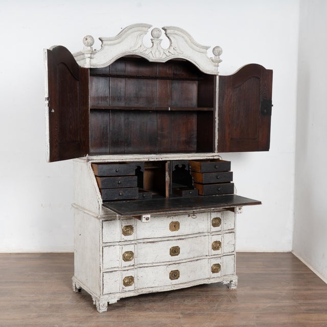 This elegant Swedish oak secretary shows off with a distinctive carved top bonnet or crown and round finials. Also known...