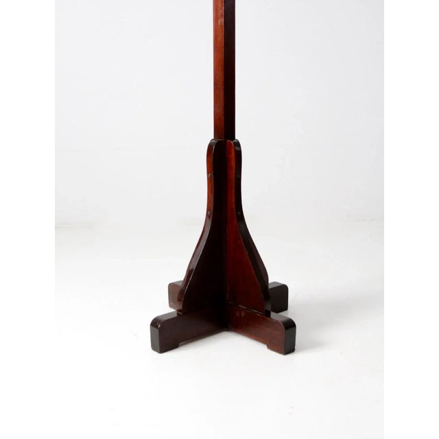 This is an antique wooden coat rack in the Mission style, featuring a solid wood base and vertical stand topped with brass...