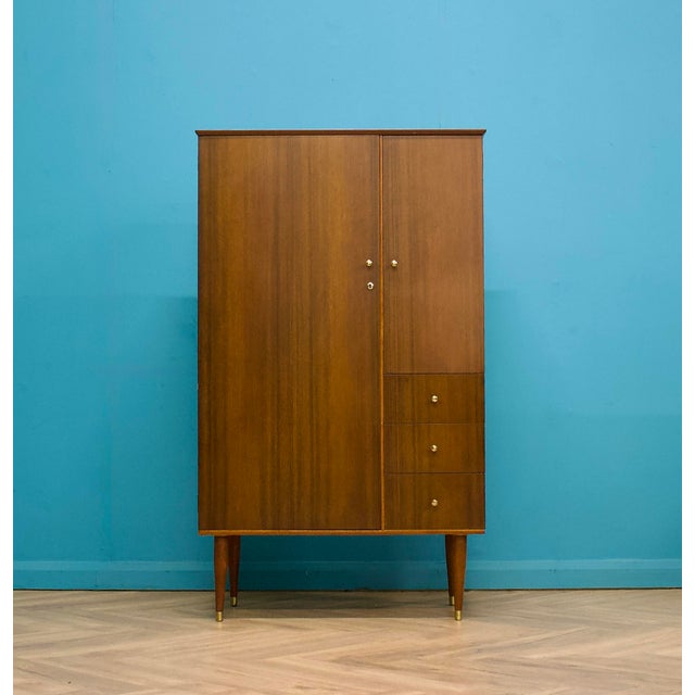 A well-proportioned mid century wardrobe by Uniflex, raised on tapered legs with brass caps. Finished in warm walnut...