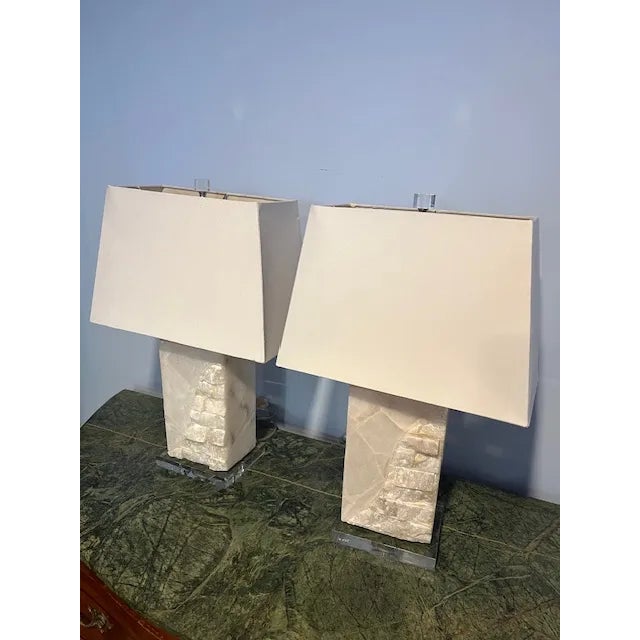 A gorgeous pair of natural white Quarts and Lucite table lamps including the shades. The lamps sit on Lucite bases and...