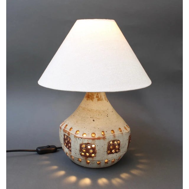 Ceramic table lamp in the style of Georges Pelletier (circa 1970s). An oatmeal colored base glaze forms the background for...