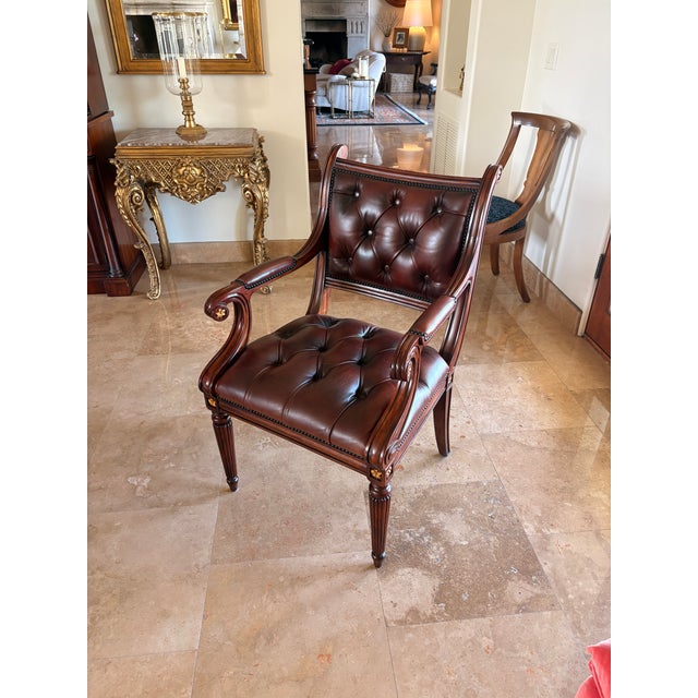 A hand carved library armchair, with an upholstered leather panel back and seat, with brass nail head trim, scroll arms,...